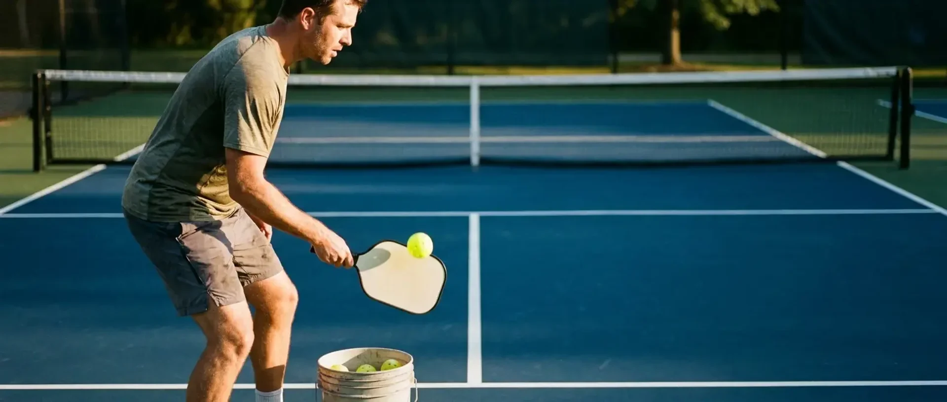 A pickleball player practices solo against a concrete wall, paddle just past contact with the ball — illustrating how to break out of 3.0 and reach 3.5.