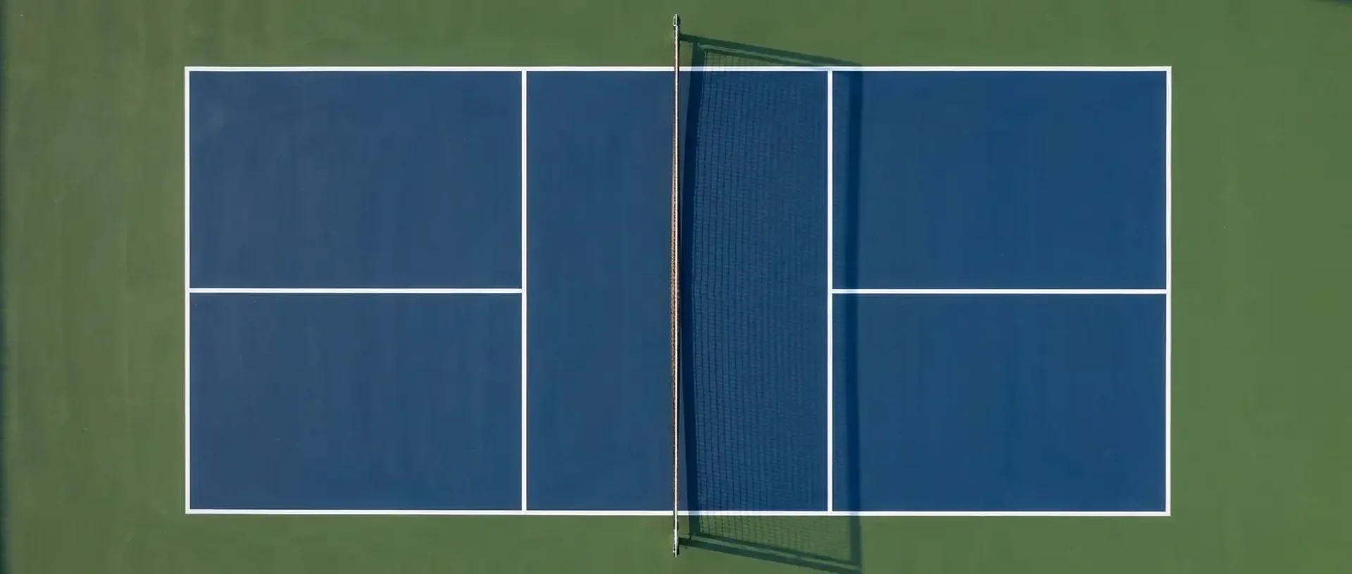 An overhead view of an empty pickleball court showing the 20x44 ft dimensions, 7 ft kitchens, service boxes, and 34-in center net — illustrating pickleball court dimensions.